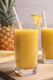 Photo of Tasty pineapple smoothie and fresh fruit on table