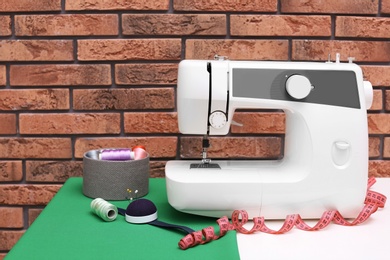 Photo of Modern sewing machine on table near brick wall