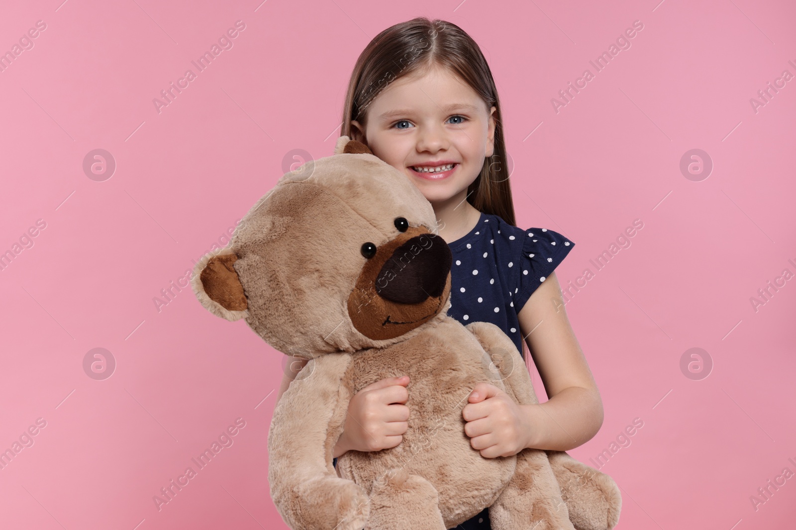 Photo of Cute little girl with teddy bear on pink background