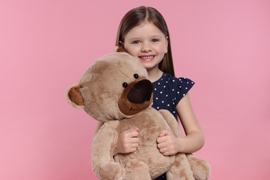 Cute little girl with teddy bear on pink background