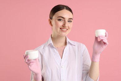 Photo of Cosmetologist with cosmetic products on pink background