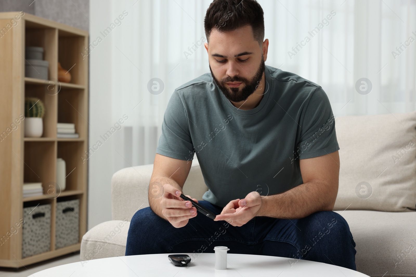 Photo of Diabetes test. Man checking blood sugar level with lancet pen at table indoors