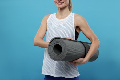 Photo of Sportswoman with fitness mat on light blue background, closeup