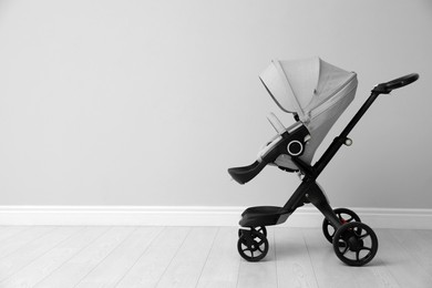 Photo of Baby carriage. Modern pram near light grey wall, space for text