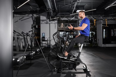 Photo of Man recording workout on camera at gym. Online fitness trainer
