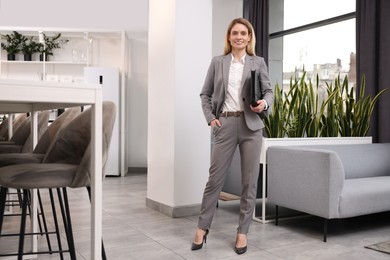 Photo of Happy real estate agent with leather portfolio indoors