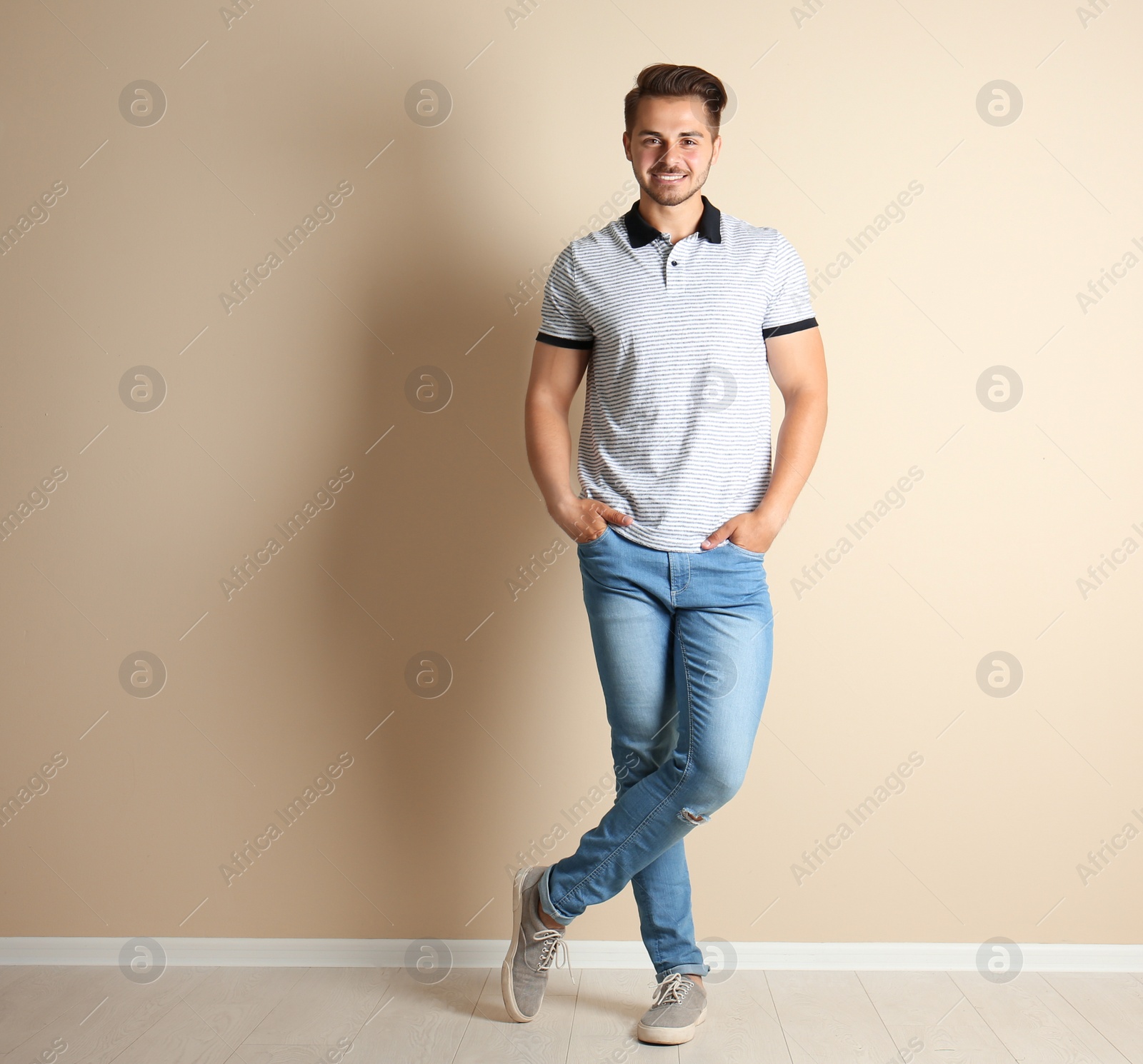 Photo of Young man in stylish jeans near light wall