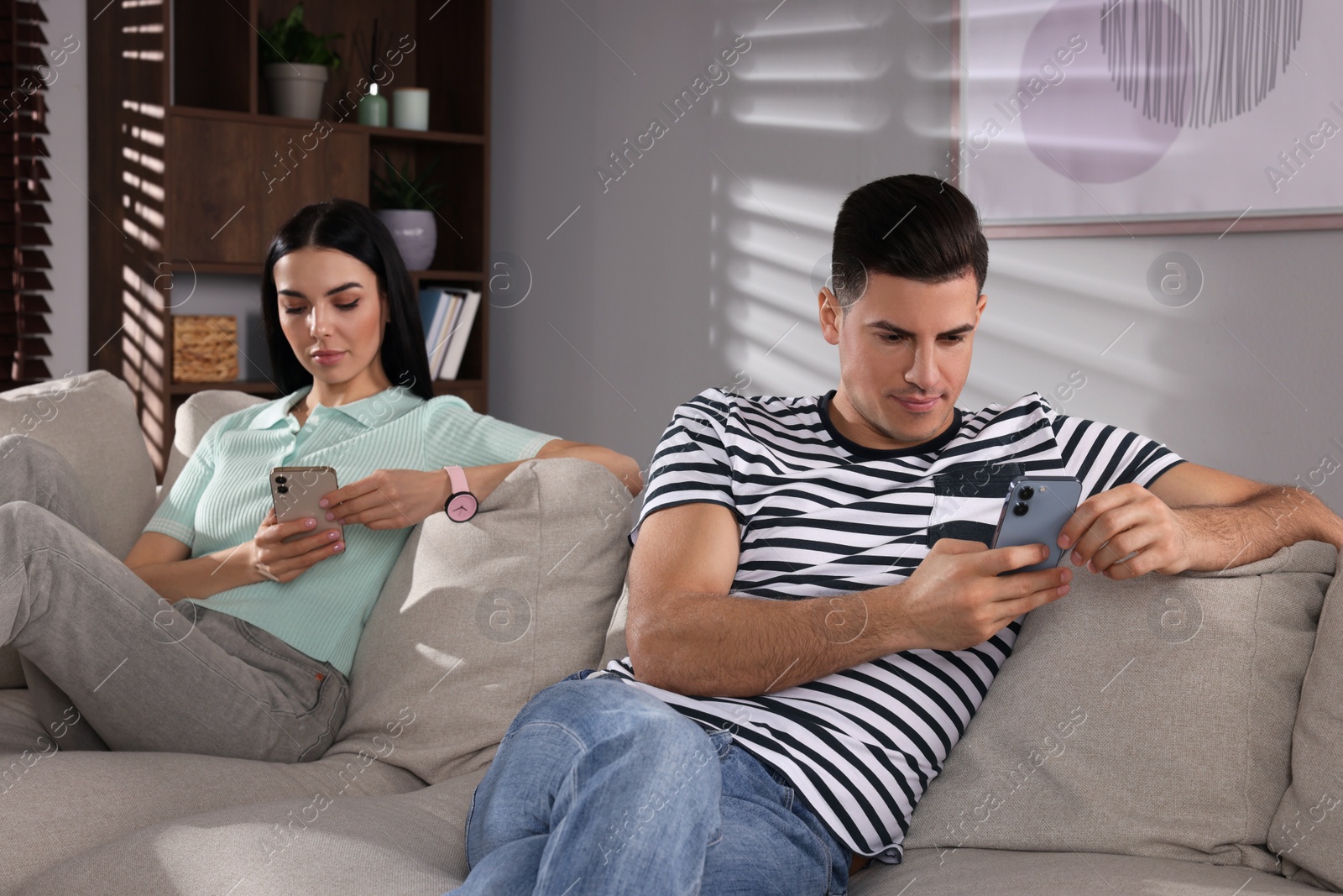 Photo of Internet addiction. Couple with smartphones on sofa in living room