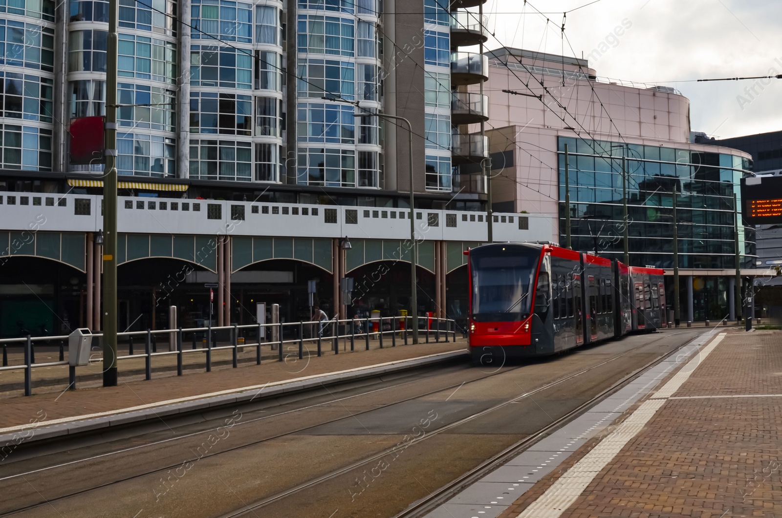 Photo of Red modern tram at station. Public transport