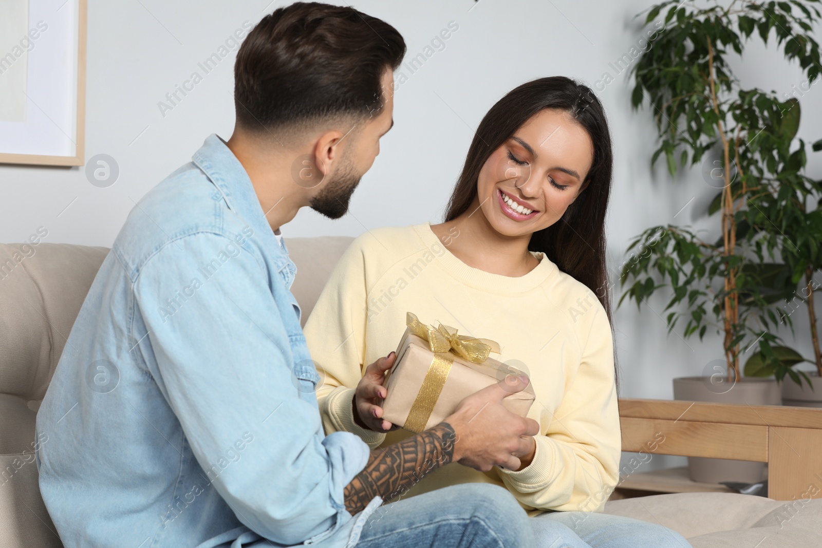 Photo of Man presenting gift to his girlfriend at home