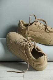 Photo of Pair of stylish beige sneakers on floor against light grey background