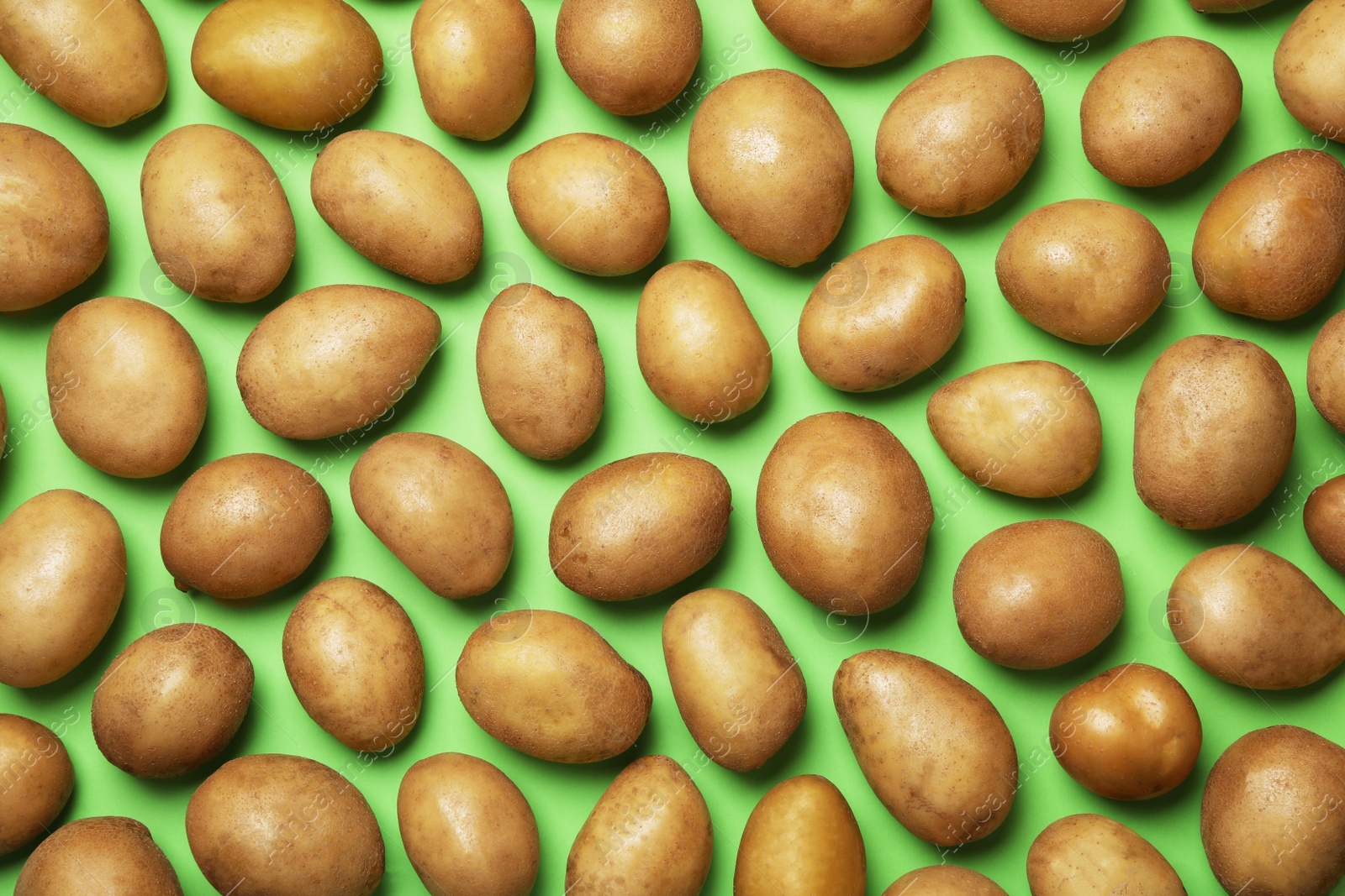 Photo of Raw fresh organic potatoes on green background, flat lay