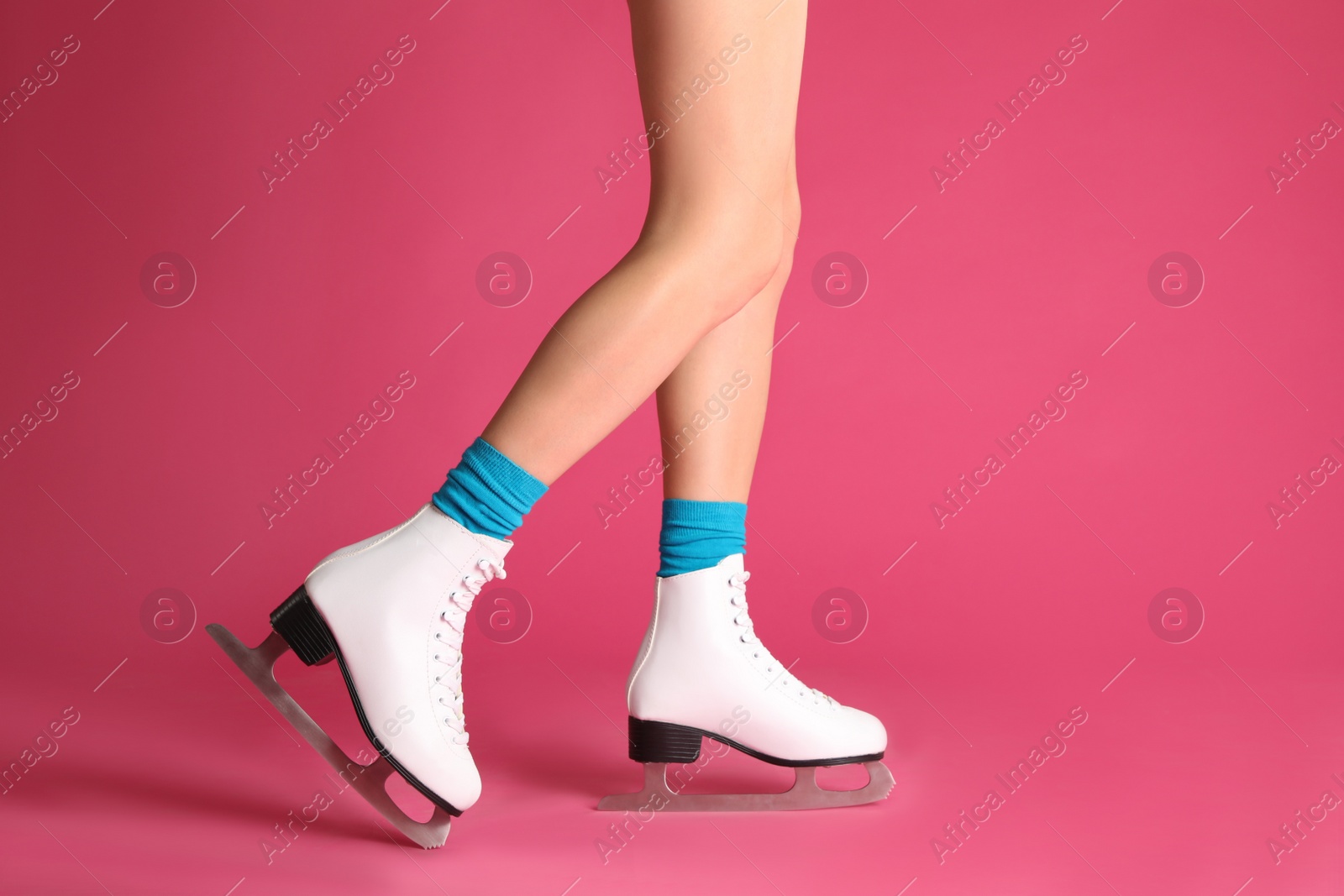 Photo of Woman in elegant white ice skates on pink background, closeup of legs. Space for text