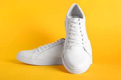 Photo of Pair of stylish white sneakers on yellow background