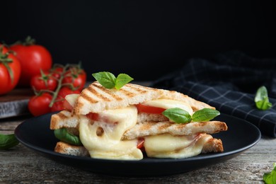 Photo of Delicious grilled sandwiches with mozzarella, tomatoes and basil on wooden table. Space for text