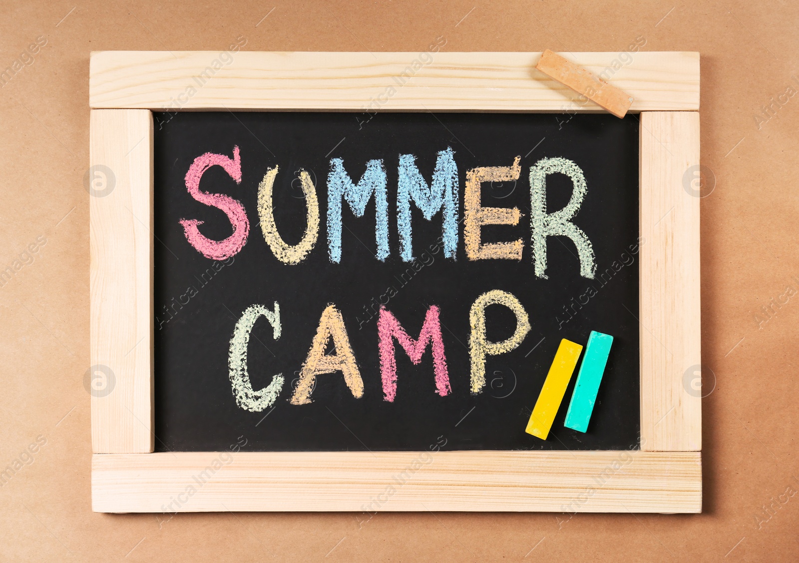 Photo of Words SUMMER CAMP written with colorful chalk on small blackboard, top view