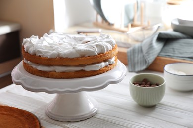 Photo of Delicious homemade sponge cakes with cream on white wooden table in kitchen. Space for text