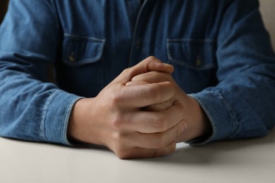 Photo of Man clenching hands at table while restraining anger, closeup