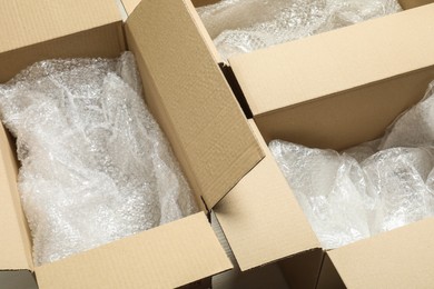Photo of Many open cardboard boxes with bubble wrap on white floor