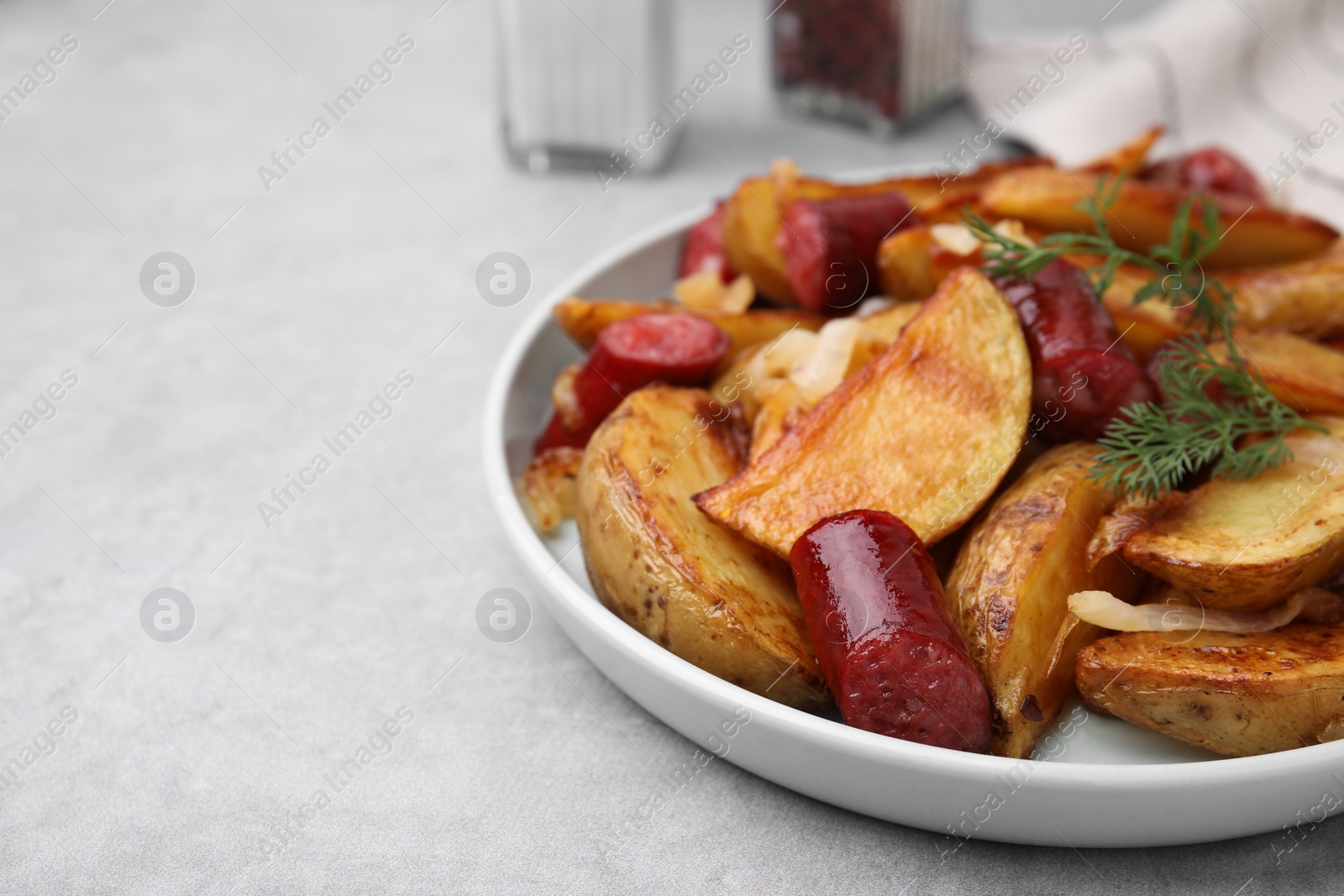 Photo of Delicious baked potato with thin dry smoked sausages, onion and dill on gray table, closeup. Space for text