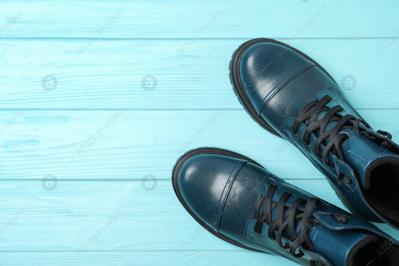 Photo of Stylish female boots on light blue wooden table, flat lay. Space for text