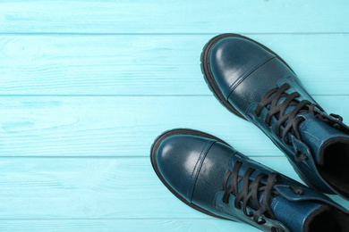 Stylish female boots on light blue wooden table, flat lay. Space for text