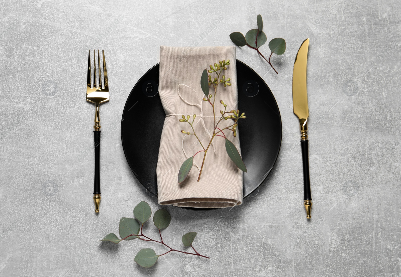 Photo of Stylish table setting with cutlery and eucalyptus leaves, flat lay