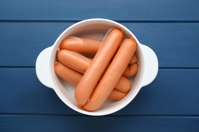 Bowl of delicious sausages on blue wooden table, top view
