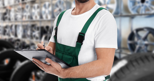 Image of Professional mechanic with clipboard at tire shop, closeup