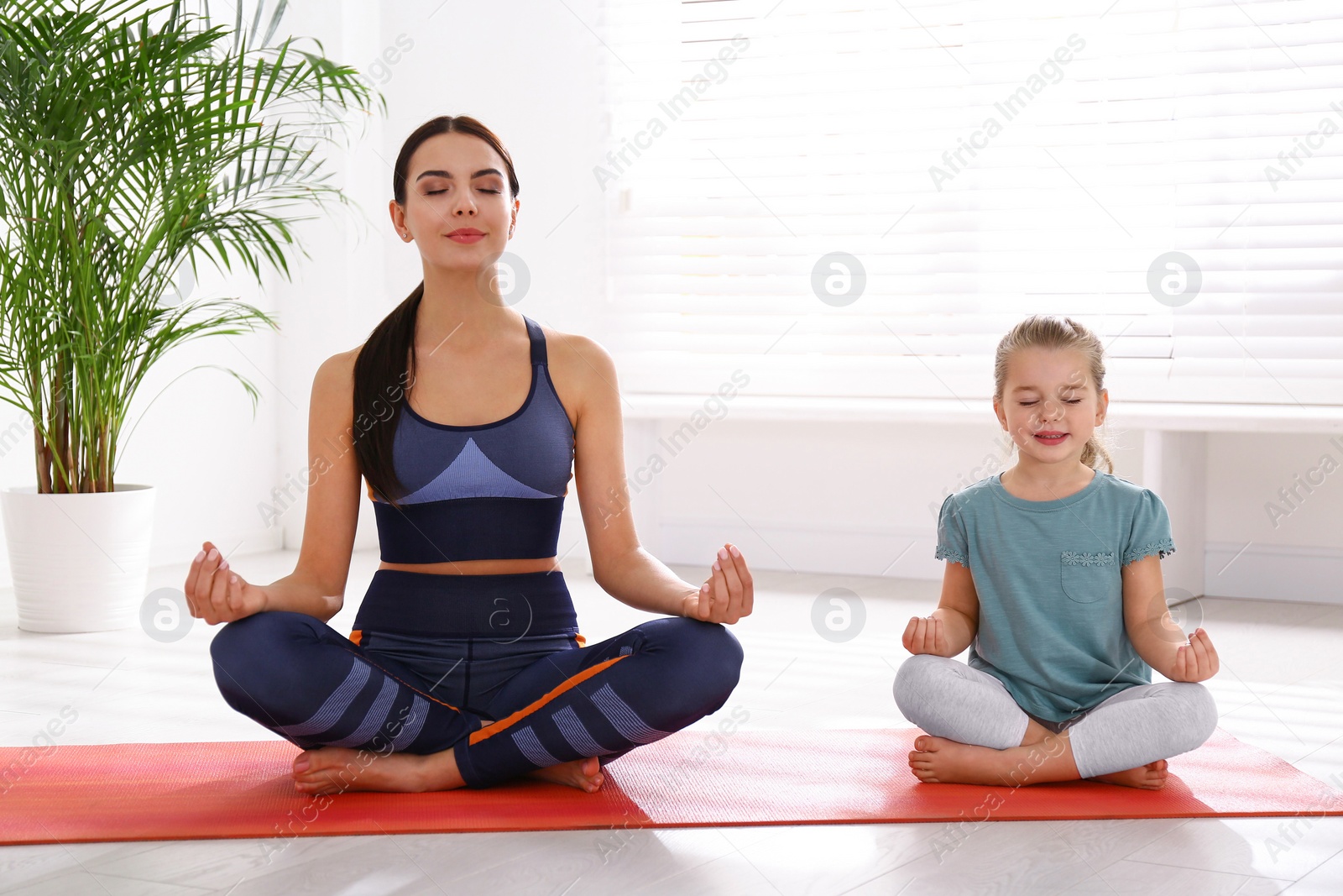 Photo of Woman and daughter meditating together at home. Fitness lifestyle