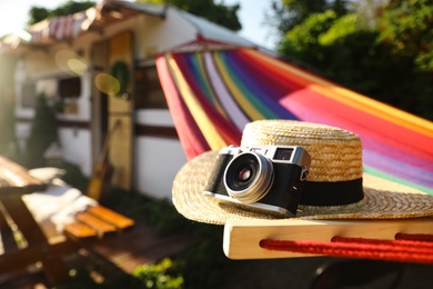 Photo of Comfortable hammock with hat and vintage camera near motorhome outdoors on sunny day, closeup