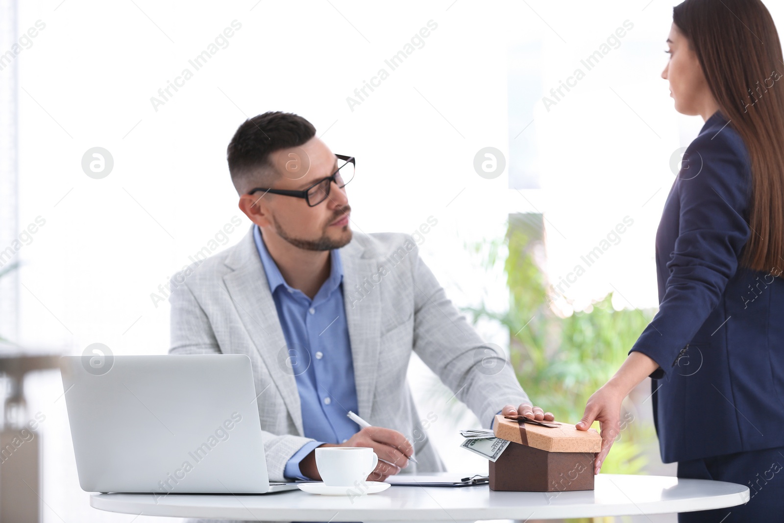 Photo of Woman giving bribe to man at table indoors