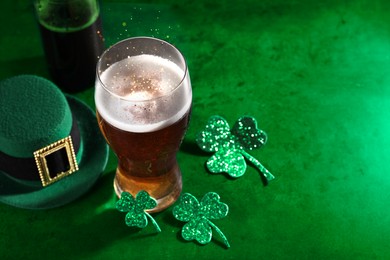 St. Patrick's day. Beer, decorative clover leaves and leprechaun hat on green table, space for text