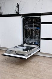 Photo of Open clean empty dishwasher in kitchen. Home appliance