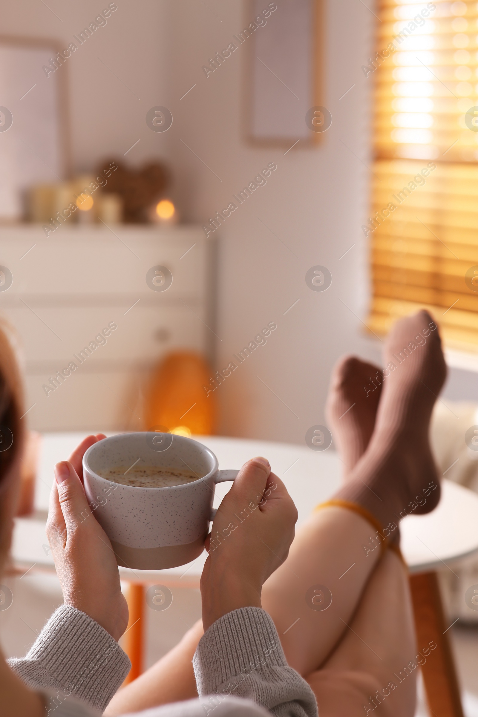 Photo of Woman with cup of aromatic coffee relaxing at home, closeup