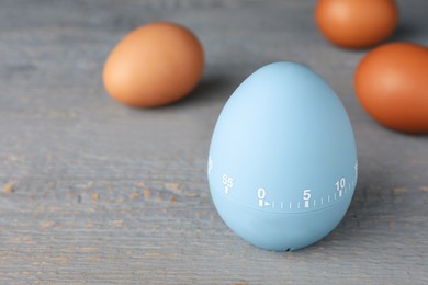 Photo of Kitchen timer and eggs on grey wooden table. Space for text