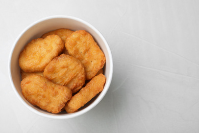 Bucket with tasty chicken nuggets on light grey table, top view. Space for text
