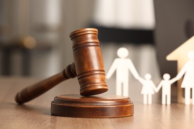 Photo of Law concept. Gavel and figures of parents with children on wooden table, closeup