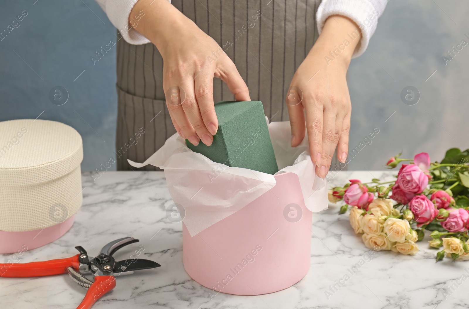 Photo of Female florist using floral foam for work at table