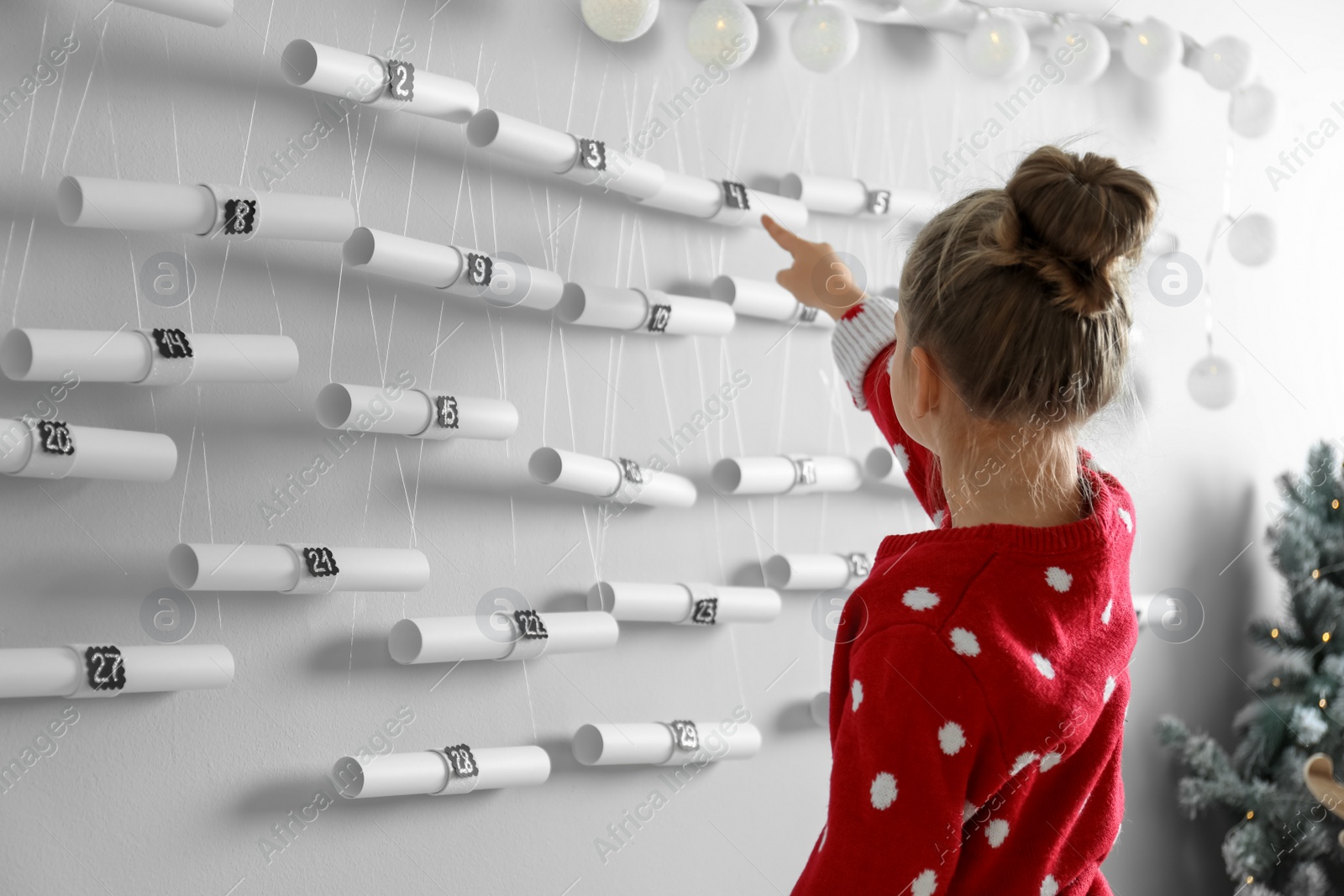 Photo of Little girl pointing at New Year advent calendar in room