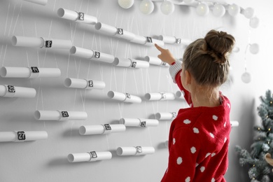 Little girl pointing at New Year advent calendar in room