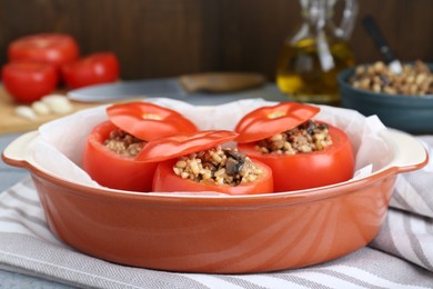 Uncooked stuffed tomatoes with minced beef, bulgur and mushrooms in baking dish on table, closeup