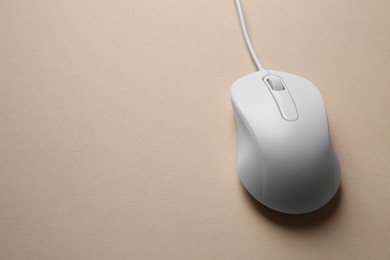 Photo of One wired mouse on beige background, closeup. Space for text