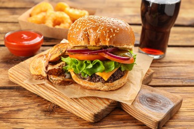 Tasty burger with potato wedges served on wooden table. Fast food