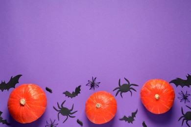 Flat lay composition with pumpkins, paper bats and spiders on purple background, space for text. Halloween decor