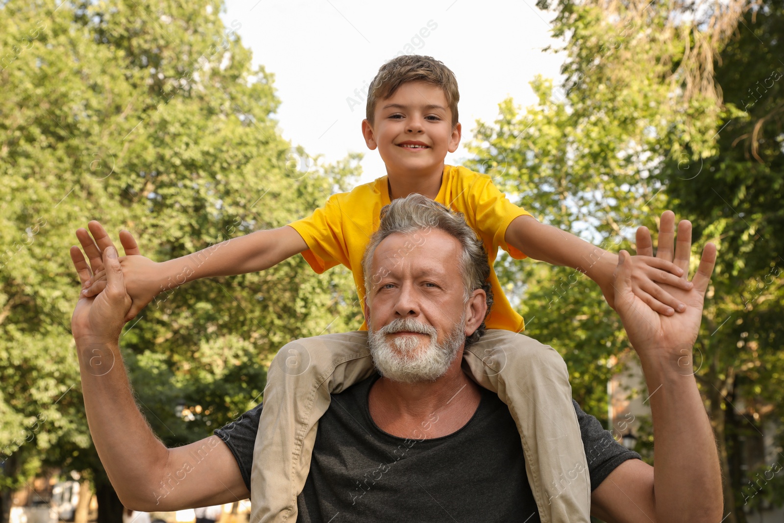 Photo of Senior man with his little grandson having fun together in park