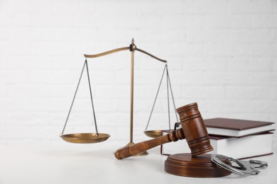 Photo of Composition with gavel and handcuffs on table against white background. Criminal law