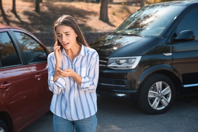Photo of Stressed woman talking on phone after car accident outdoors