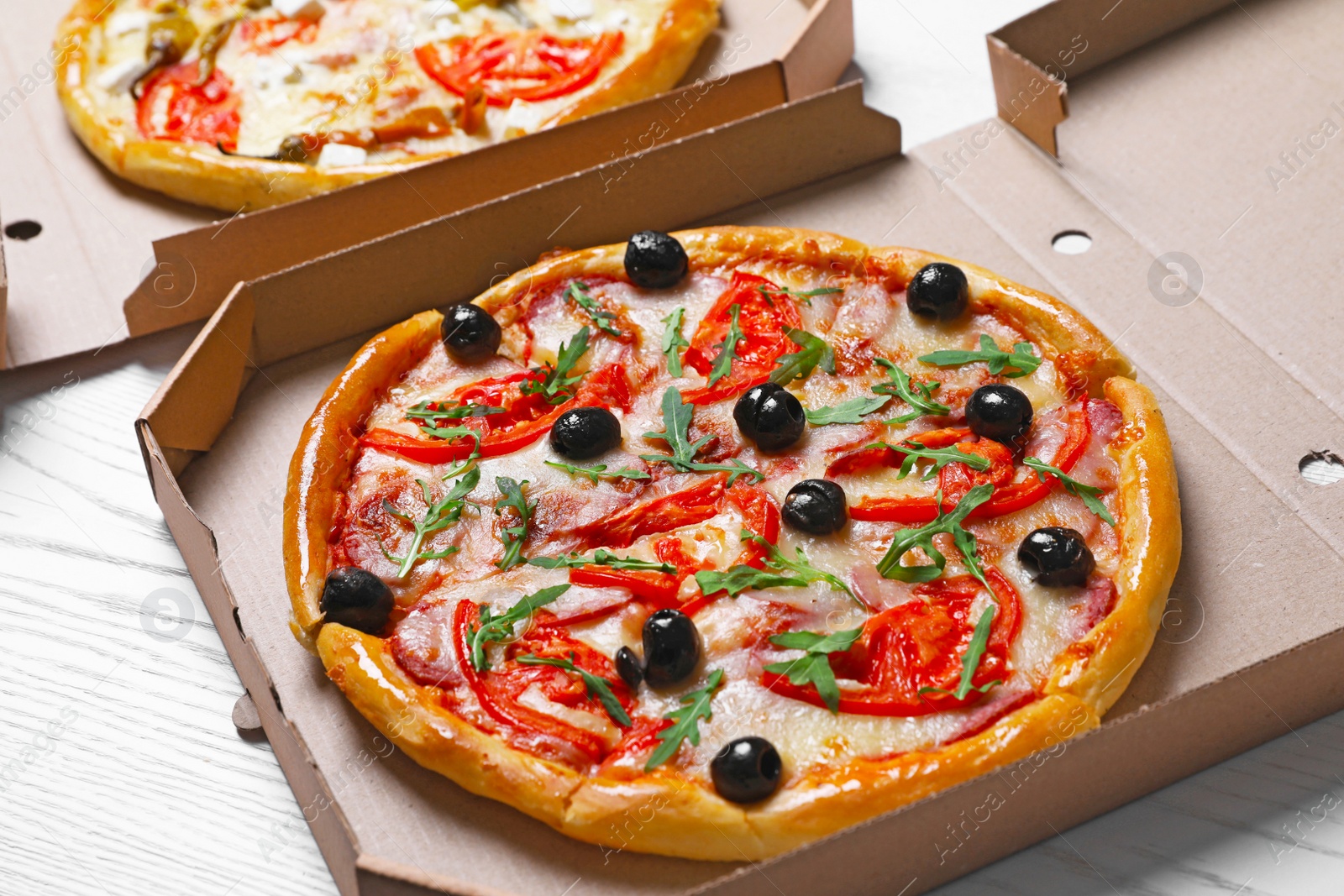 Photo of Cardboard boxes with tasty pizzas on wooden table