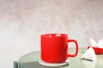 Cup and pyramid teabag on table against color background